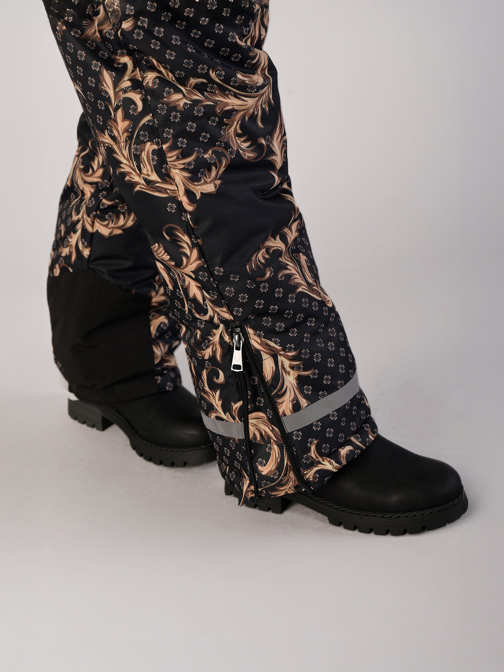 Luxury girls’ snowsuit with golden baroque print on black, handcrafted in Europe from waterproof polyester with Sorona® plant-based insulation. Warm and breathable winter overall for kids, certified Oeko-Tex Standard 100, perfect for skiing and cold weather up to −25°C.