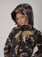 Luxury girls’ snowsuit with golden baroque print on black, handcrafted in Europe from waterproof polyester with Sorona® plant-based insulation. Warm and breathable winter overall for kids, certified Oeko-Tex Standard 100, perfect for skiing and cold weather up to −25°C.