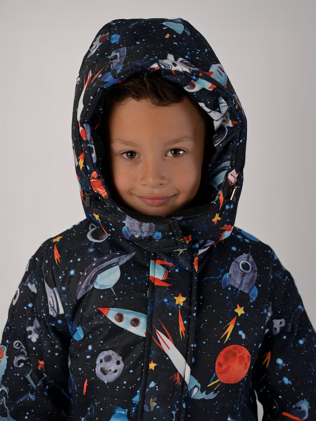 Luxury kids’ snowsuit with cosmic space print featuring rockets and planets, waterproof and breathable, Sorona® eco insulation, Oeko-Tex certified, handcrafted in Europe for warmth to −25°C.